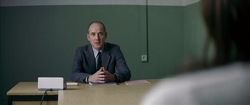 Movie still from “The Lives of Others” (2006), directed by Florian Henckel von Donnersmarck – A man sitting at a table in front of papers; Medium shot, Over the shoulder angle
