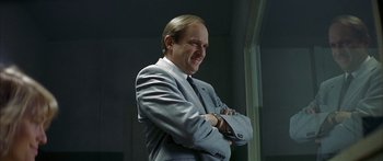 Movie still from “The Lives of Others” (2006), directed by Florian Henckel von Donnersmarck – A man in a suit and tie with his arms crossed; Close Up shot, Low angle