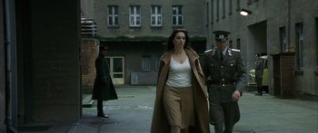Movie still from “The Lives of Others” (2006), directed by Florian Henckel von Donnersmarck – A woman walking down a street with a man in uniform behind her; Wide shot, Over the shoulder angle