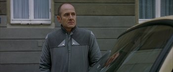 Movie still from “The Lives of Others” (2006), directed by Florian Henckel von Donnersmarck – A man standing next to a car outside of a house; Close Up shot, Over the shoulder angle