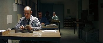 Movie still from “The Lives of Others” (2006), directed by Florian Henckel von Donnersmarck – A group of men sitting at a table in a room; Medium shot, Over the shoulder angle