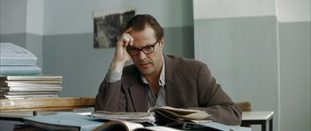 Movie still from “The Lives of Others” (2006), directed by Florian Henckel von Donnersmarck – A man sitting at a table reading a magazine; Close Up shot, Over the shoulder angle