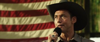 Movie still from “Real Steel” (2011), directed by Shawn Levy – A man in a cowboy hat is holding a microphone; Close Up shot, Low angle
