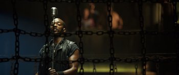 Movie still from “Real Steel” (2011), directed by Shawn Levy – A man in a leather jacket holding a microphone; Medium shot, Low angle