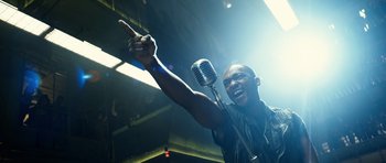 Movie still from “Real Steel” (2011), directed by Shawn Levy – A man holding a microphone and pointing to the sky; Close Up shot, Low angle