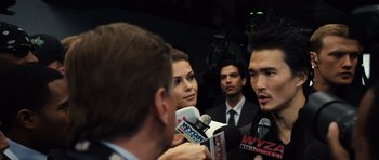 Movie still from “Real Steel” (2011), directed by Shawn Levy – A group of people in business suits are being interviewed by reporters; Close Up shot, Over the shoulder angle