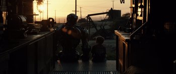 Movie still from “Real Steel” (2011), directed by Shawn Levy – A man sitting on the ground next to a child; Wide shot, Low angle