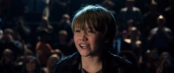 Movie still from “Real Steel” (2011), directed by Shawn Levy – A young boy smiling for the camera in a crowd; Close Up shot, High angle