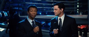 Movie still from “Real Steel” (2011), directed by Shawn Levy – Two men in suits are holding microphones and talking to each other; Medium shot, High angle
