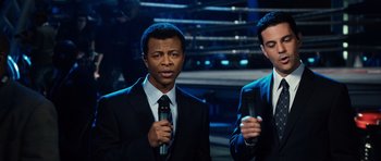 Movie still from “Real Steel” (2011), directed by Shawn Levy – Two men in suits are holding microphones and talking; Medium shot, High angle