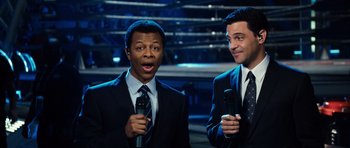 Movie still from “Real Steel” (2011), directed by Shawn Levy – Two men in suits are holding microphones and talking; Medium shot, High angle