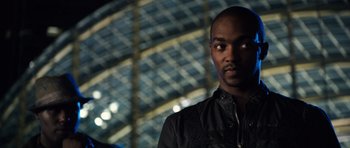 Movie still from “Real Steel” (2011), directed by Shawn Levy – A man in a black jacket is standing in front of a building; Close Up shot, Over the shoulder angle