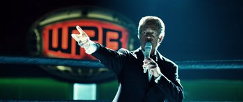 Movie still from “Real Steel” (2011), directed by Shawn Levy – A man in a black suit is holding a microphone; Close Up shot, Low angle