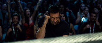Movie still from “Real Steel” (2011), directed by Shawn Levy – A man with his hand up to his face in front of a group of people; Close Up shot, Low angle