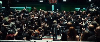 Movie still from “Real Steel” (2011), directed by Shawn Levy – A group of people taking pictures of a person in a boxing ring; Wide shot, High angle