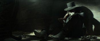 Movie still from “The Lone Ranger” (2013), directed by Gore Verbinski – A man in cowboy boots and a white hat sitting on the ground; Wide shot, Low angle