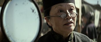 Movie still from “The Lone Ranger” (2013), directed by Gore Verbinski – An older woman wearing glasses looking in a mirror; Close Up shot, Over the shoulder angle