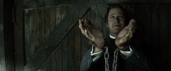 Movie still from “The Lone Ranger” (2013), directed by Gore Verbinski – A man in chains holding a knife in his hands; Close Up shot, Low angle