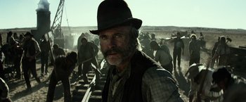 Movie still from “The Lone Ranger” (2013), directed by Gore Verbinski – An old man with a beard and a hat is standing in front of a group of men; Close Up shot, Low angle