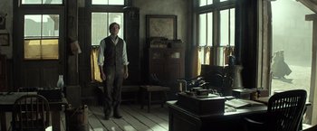 Movie still from “The Lone Ranger” (2013), directed by Gore Verbinski – A man standing in front of a desk in a room; Wide shot, Low angle