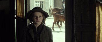 Movie still from “The Lone Ranger” (2013), directed by Gore Verbinski – A young boy in a hat standing next to a horse; Close Up shot, Low angle