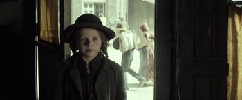 Movie still from “The Lone Ranger” (2013), directed by Gore Verbinski – A young boy wearing a hat standing in front of a window; Medium shot, Low angle