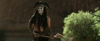 Movie still from “The Lone Ranger” (2013), directed by Gore Verbinski – A man in native american garb holding a spear; Medium shot, Over the shoulder angle