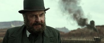 Movie still from “The Lone Ranger” (2013), directed by Gore Verbinski – A man with a beard wearing a suit and a hat; Close Up shot, Over the shoulder angle