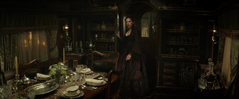 Movie still from “The Lone Ranger” (2013), directed by Gore Verbinski – A woman in a long black dress standing in front of a dining room table; Wide shot, Over the shoulder angle