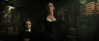 Movie still from “The Lone Ranger” (2013), directed by Gore Verbinski – A woman in a black dress standing next to a boy; Medium shot, Low angle
