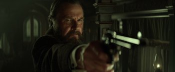 Movie still from “The Lone Ranger” (2013), directed by Gore Verbinski – A man with a beard holding a gun in a dark room; Close Up shot, Low angle
