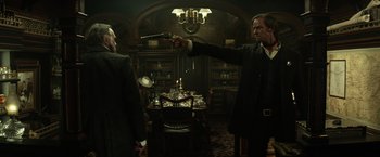 Movie still from “The Lone Ranger” (2013), directed by Gore Verbinski – Two men in suits and ties are holding guns in a room; Medium shot, Over the shoulder angle
