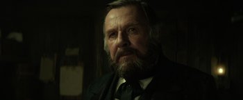 Movie still from “The Lone Ranger” (2013), directed by Gore Verbinski – An old man with a beard wearing a suit and tie; Close Up shot, Low angle