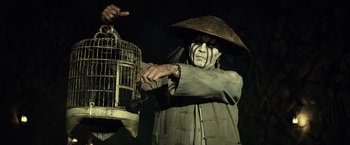 Movie still from “The Lone Ranger” (2013), directed by Gore Verbinski – A man in a hat and mask holding a bird cage; Close Up shot, Low angle