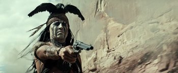 Movie still from “The Lone Ranger” (2013), directed by Gore Verbinski – A man with a gun in his hand and a bird on his head; Medium shot, Low angle