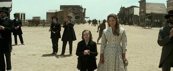 Movie still from “The Lone Ranger” (2013), directed by Gore Verbinski – A group of people standing on a dirt road; Medium shot, Over the shoulder angle