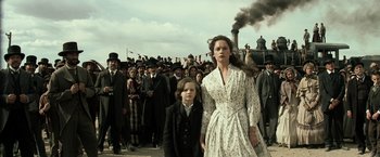 Movie still from “The Lone Ranger” (2013), directed by Gore Verbinski – A woman and a boy are standing in front of a crowd of onlookers; Medium shot, Low angle