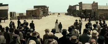 Movie still from “The Lone Ranger” (2013), directed by Gore Verbinski – A group of people standing on a dirt field; Extreme Wide shot, Over the shoulder angle