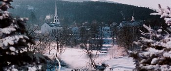 Movie still from “The Long Kiss Goodnight” (1996), directed by Renny Harlin – A view of a town in the snow with a church steeple in the background; Extreme Wide shot, High angle