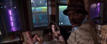 Movie still from “The Long Kiss Goodnight” (1996), directed by Renny Harlin – A man and a woman sitting in a room; Medium shot, Over the shoulder angle