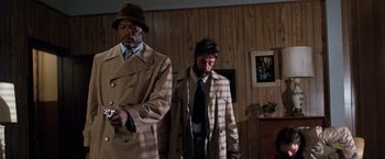 Movie still from “The Long Kiss Goodnight” (1996), directed by Renny Harlin – Two men dressed in trench coats and hats; Medium shot, Low angle