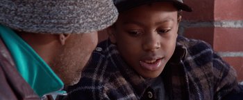 Movie still from “The Long Kiss Goodnight” (1996), directed by Renny Harlin – A young boy wearing a plaid shirt and a hat; Close Up shot, Over the shoulder angle