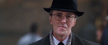 Movie still from “The Long Kiss Goodnight” (1996), directed by Renny Harlin – An older man wearing a hat and glasses; Close Up shot, Over the shoulder angle