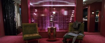 Movie still from “The Long Kiss Goodnight” (1996), directed by Renny Harlin – Two chairs in front of a window with a fountain in it; Wide shot, High angle