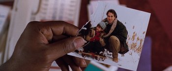 Movie still from “The Long Kiss Goodnight” (1996), directed by Renny Harlin – A hand holding a piece of paper with a picture of a man and a child; Extreme Close Up shot, High angle