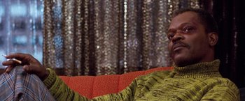 Movie still from “The Long Kiss Goodnight” (1996), directed by Renny Harlin – A person sitting on a couch in a room; Close Up shot, Low angle