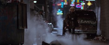 Movie still from “The Long Kiss Goodnight” (1996), directed by Renny Harlin – A man and a woman standing on a sidewalk; Wide shot, Low angle