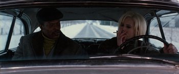 Movie still from “The Long Kiss Goodnight” (1996), directed by Renny Harlin – A man and a woman sitting in the back seat of a car; Medium shot, Over the shoulder angle