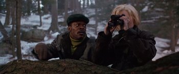 Movie still from “The Long Kiss Goodnight” (1996), directed by Renny Harlin – A man taking a picture of a woman with a camera; Medium shot, Over the shoulder angle