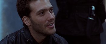 Movie still from “The Long Kiss Goodnight” (1996), directed by Renny Harlin – Close up of a man in a leather jacket looking at the camera; Close Up shot, Over the shoulder angle